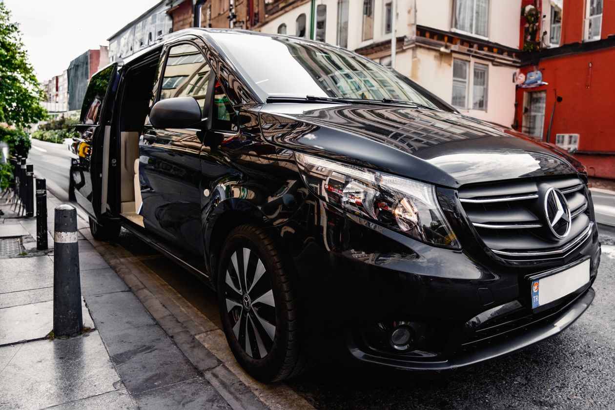 Schwarze Mercedes-Benz Großraumlimousine mit geöffneter Schiebetür – Familien-Transfer mit Kindersitz in München